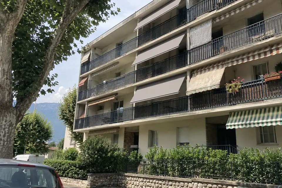 Immeuble de copropriété dont les balcons portent des stores bannes de la même toile